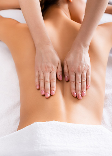 Massage therapist hands on woman's back while lying down