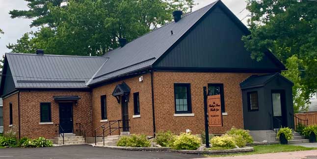 The Heritage House building with brown brick and black metal roof and doorways