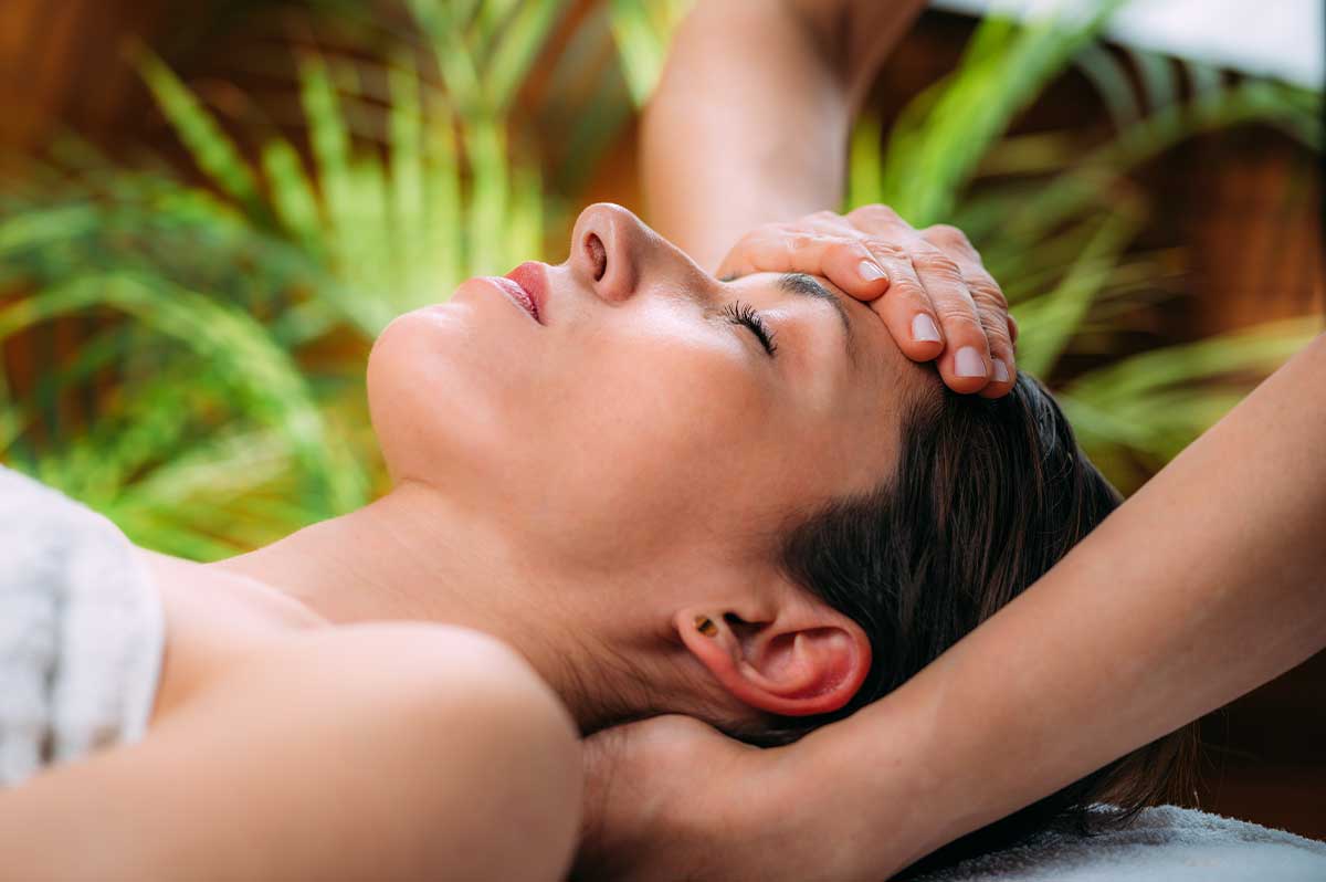 Woman laying down at spa while receiving osteopathy treatment on neck and head